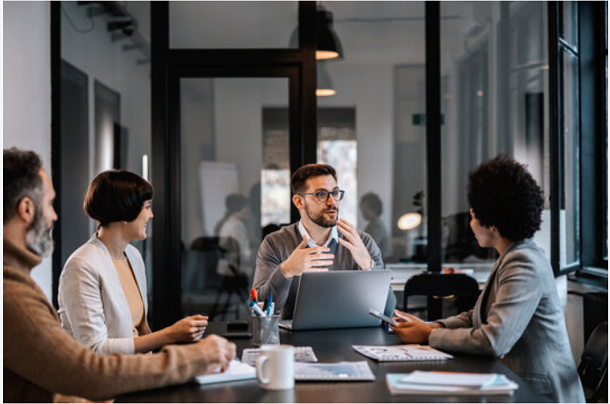 People at a desk with computers talking
